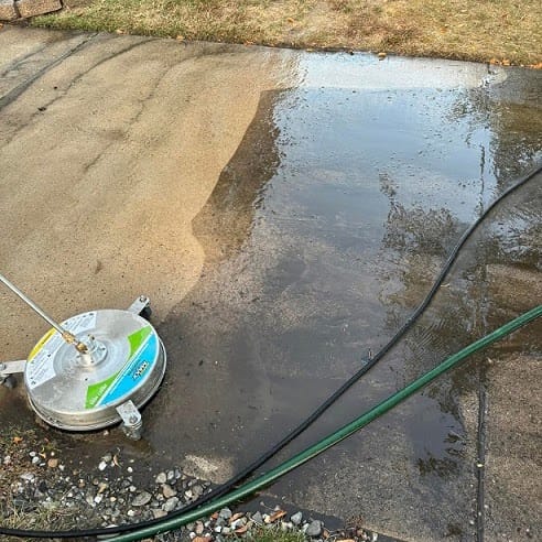 A rotary surface cleaner leaving a clean stripe on a concrete patio